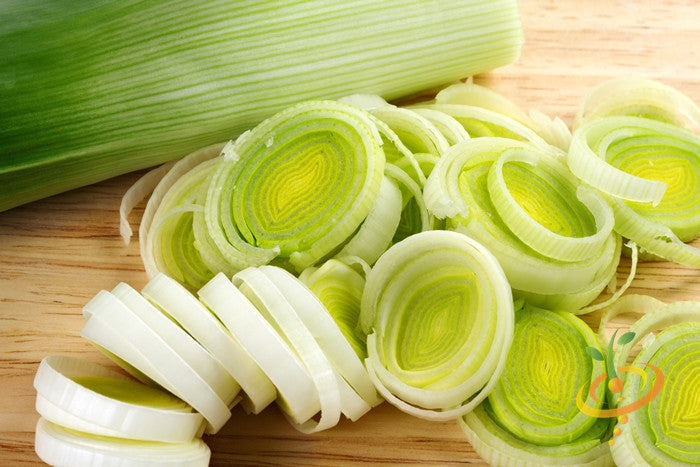 Close-up of fresh sliced leek showing green and white layers on wooden cutting board