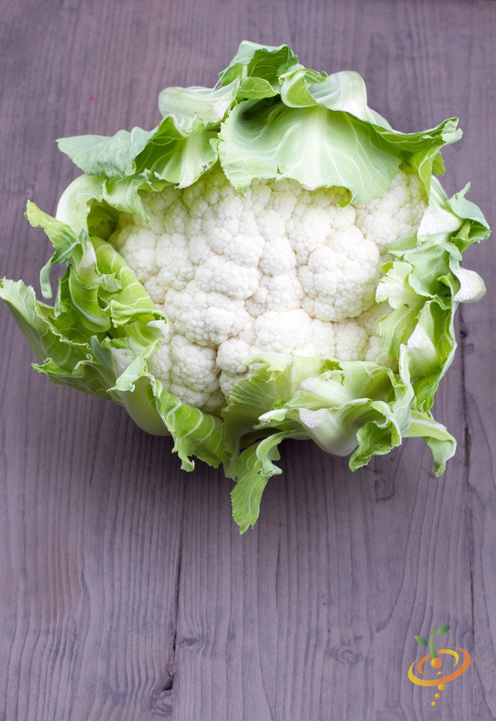 Fresh Igloo cauliflower head with green leaves on wooden surface