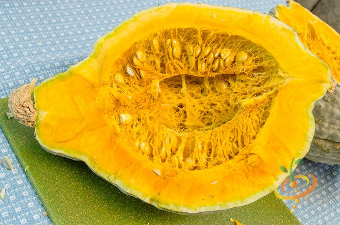 Winter Hubbard squash with golden seeds, fresh and ripe, displayed on a rustic wooden surface.
